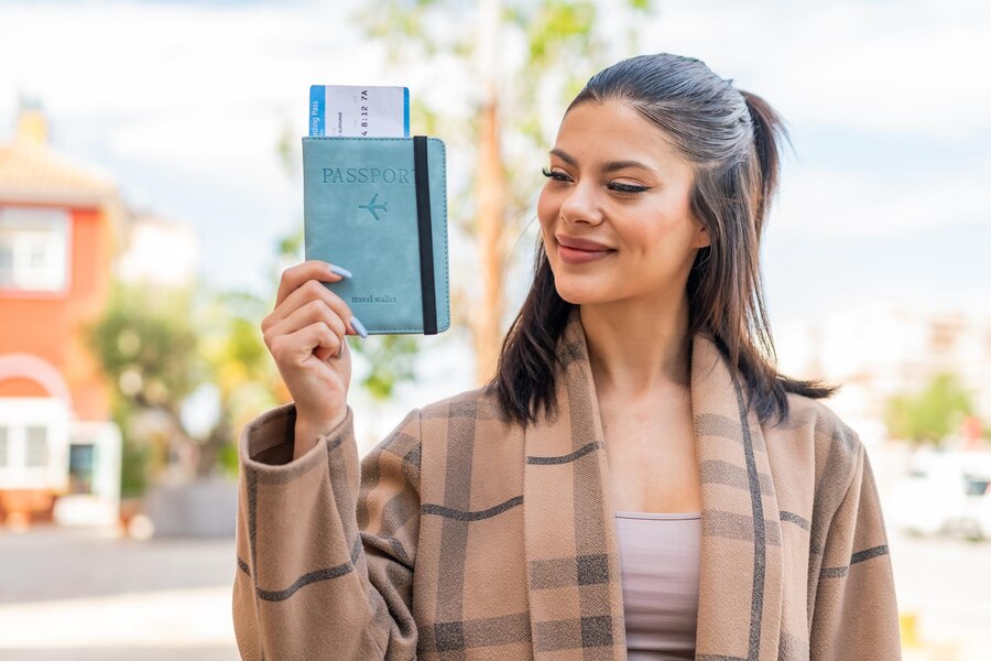 young pretty woman holding passport outdoors with happy expression 1368 482625